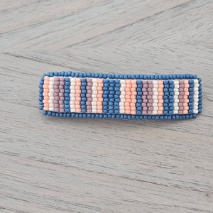 May include: A beaded hair clip with a striped pattern in shades of blue, pink, and white.