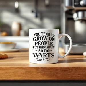 May include: White ceramic coffee mug with black text that reads "You tend to grow on people but then again so do warts".