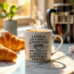 May include: White ceramic mug with a black design that reads "I could eat a bowl of alphabet soup and crap out a smarter sentence than that". The mug is filled with a hot beverage and steam is rising from the mug.