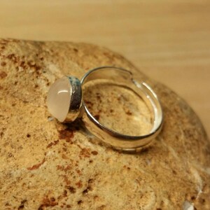 May include: A silver adjustable ring with a clear, round, cabochon gemstone.