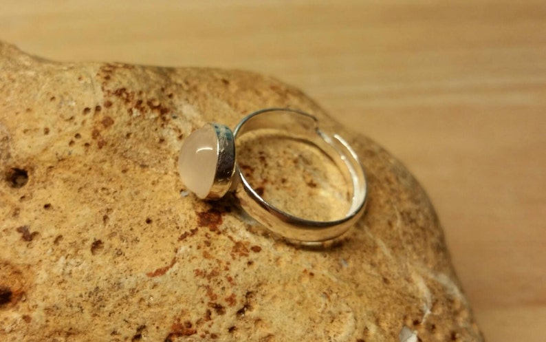 May include: A silver adjustable ring with a clear, round, cabochon gemstone.