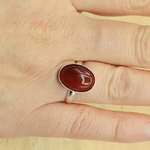 May include: A silver ring with a brown oval carnelian gemstone.