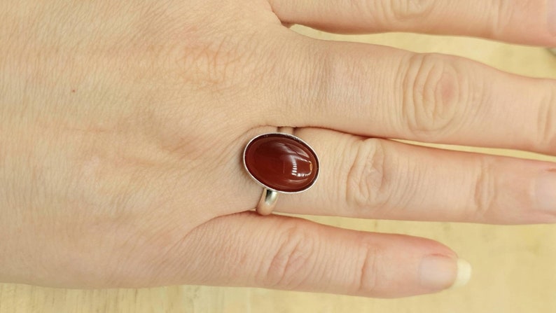 May include: A silver ring with a brown oval carnelian gemstone.
