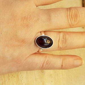 May include: A silver ring with a dark red oval gemstone.