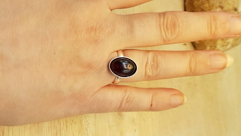 May include: A silver ring with a dark red oval gemstone.