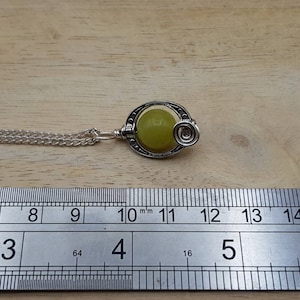 May include: A silver necklace with a green stone pendant. The pendant is round and has a silver swirl design. The necklace is 11 inches long.