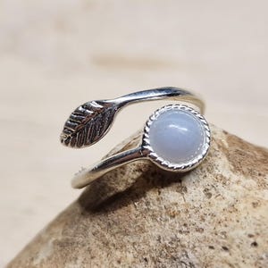 May include: A silver ring featuring a blue agate stone and a leaf design. The ring is adjustable and can be worn on any finger.