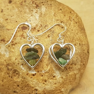 May include: Silver heart shaped earrings with green gemstone chips inside.