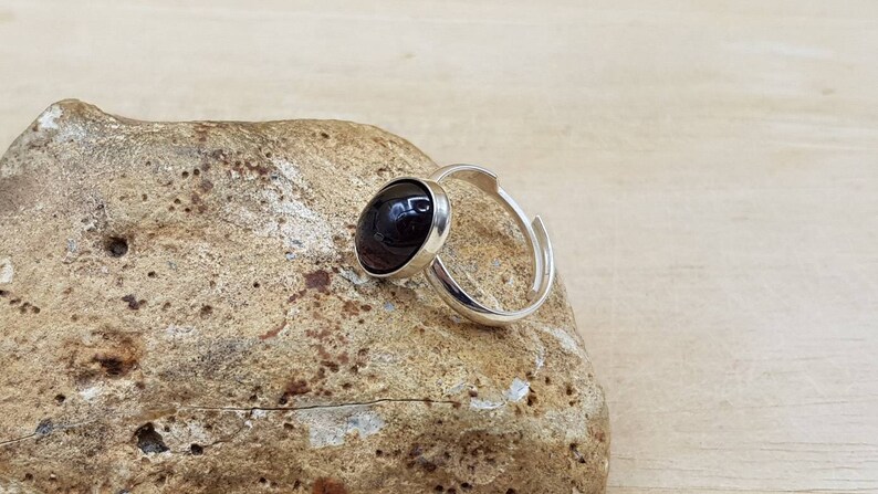 May include: A silver adjustable ring with a black oval gemstone.