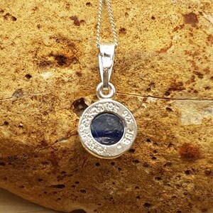 May include: A silver pendant necklace with a round blue stone set in a silver bezel. The pendant is inscribed with the words "925 Sterling Silver".