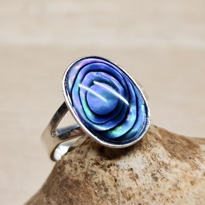 May include: A silver ring featuring a blue and iridescent abalone shell oval inlay.