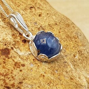 May include: A silver pendant necklace with a blue gemstone set in a silver floral design.