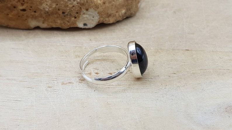 May include: A silver adjustable ring with a black oval gemstone.