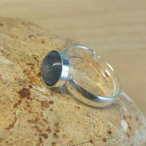 May include: A silver ring with a round, dark blue gemstone.