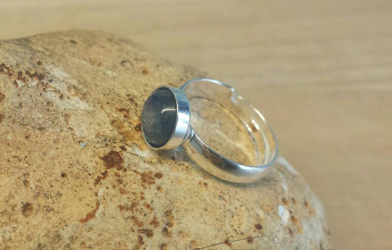 May include: A silver ring with a round, dark blue gemstone.