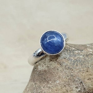 May include: A silver ring with a round blue gemstone set in the center.