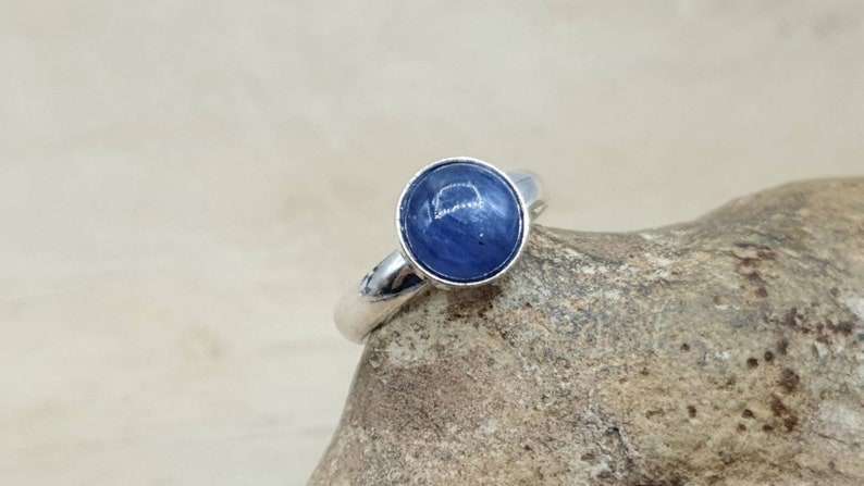 May include: A silver ring with a round blue gemstone set in the center.