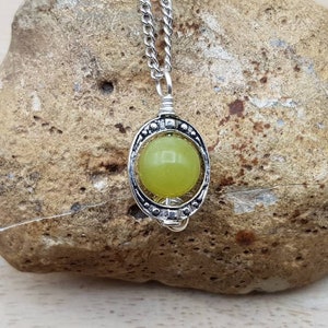 May include: A silver chain necklace with a pendant featuring a round, light green stone set in a silver frame.