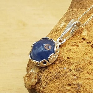 May include: A silver pendant necklace with a blue gemstone set in a silver filigree design.
