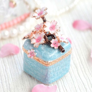 Caja de cristal para anillos de compromiso y matrimonio con diseño de flor de cerezo, ideal como regalo interior.