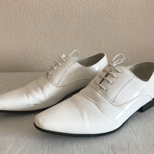 May include: Two pairs of white leather dress shoes with lace-up fastenings.