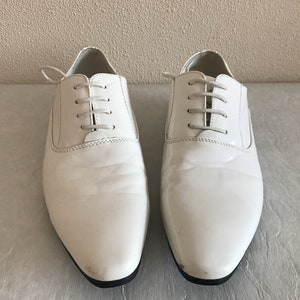 May include: A pair of white leather lace-up shoes with a pointed toe.