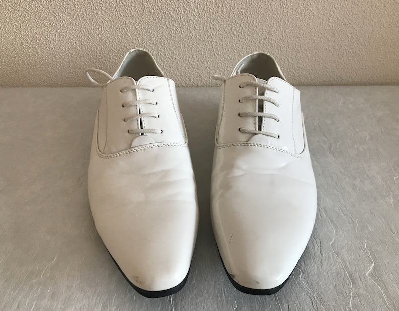 May include: A pair of white leather lace-up shoes with a pointed toe.