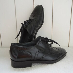 May include: A pair of black leather brogue shoes with lace-up closures. The shoes have a wingtip design and a decorative pattern.