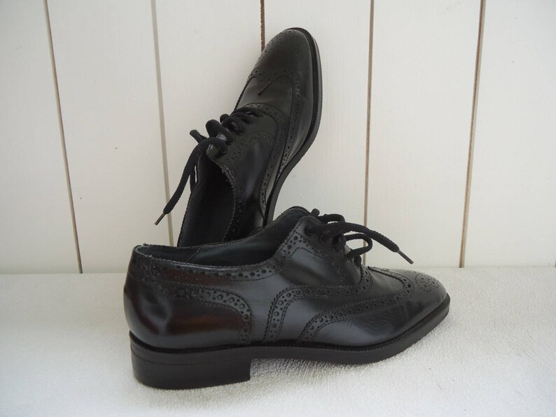 May include: A pair of black leather brogue shoes with lace-up closures. The shoes have a wingtip design and a decorative pattern.