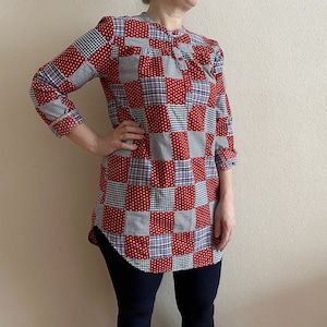 Puede incluir: Una camisa de túnica a cuadros rojos, azules y blancos con cuello y mangas largas.