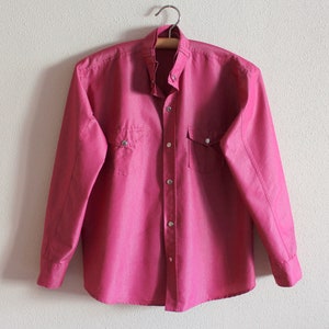 May include: A long-sleeved, pink button-down shirt with two chest pockets and a pointed collar.
