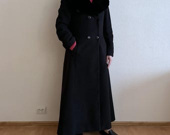 Può includere: Un cappotto lungo nero con collo in ecopelliccia e chiusura a doppio petto. Il cappotto ha tasche e un design classico. Adatto per il clima freddo, misura circa 150 cm di lunghezza.