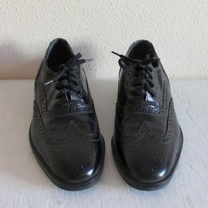 May include: A pair of black leather brogue shoes with lace-up closures. The shoes have a classic design with wingtip detailing and a polished finish.