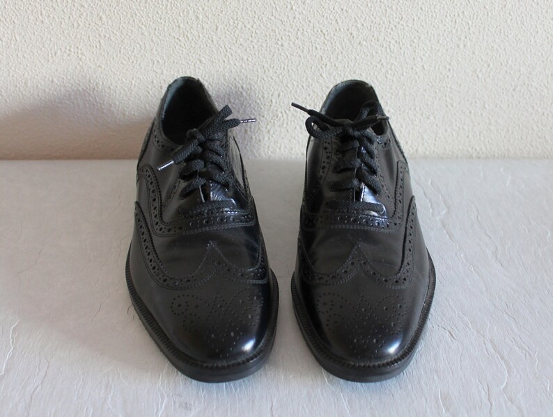 May include: A pair of black leather brogue shoes with lace-up closures. The shoes have a classic design with wingtip detailing and a polished finish.