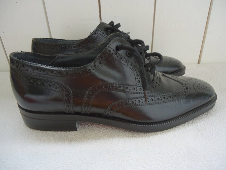May include: A pair of black leather brogue shoes with lace-up closures. The shoes have a wingtip design and a polished finish.