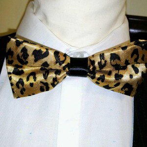 May include: A gold and black bow tie with a leopard print pattern.
