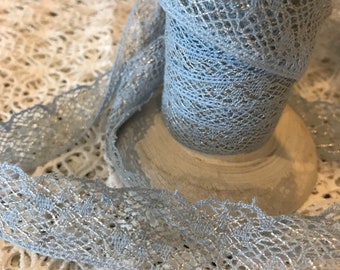 May include: A spool of light blue lace trim with silver thread woven throughout. The lace has a delicate, scalloped edge.