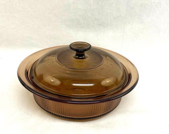 Peut inclure: Un plat à casserole en verre brun avec un couvercle assorti. Le plat est de forme ronde avec un extérieur nervuré et un couvercle en verre transparent avec une poignée en forme de bouton. Le couvercle a un motif décoratif.