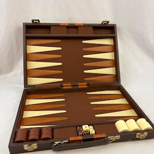 May include: Open backgammon set with brown, tan, and cream colors. The set includes dice, game pieces, and a carrying handle. The game board is open, showing the playing surface.
