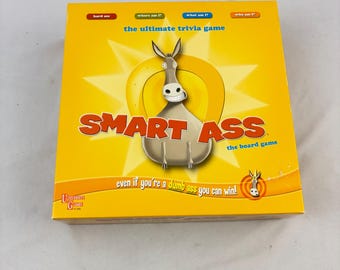 Peut inclure: Une boîte de jeu de société jaune avec le titre "SMART ASS" et une illustration d'âne de dessin animé. La boîte comprend également le texte "the ultimate trivia game" et "even if you're a dumb ass you can win!"