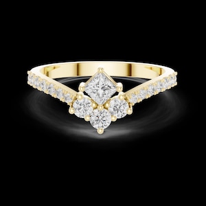 May include: A yellow gold ring featuring a central princess-cut diamond set above three round brilliant-cut diamonds in a cluster arrangement. The band is V-shaped and accented with a row of small round diamonds along both sides of the shank.