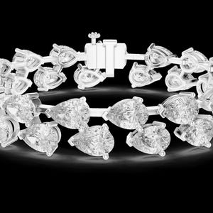May include: A dazzling bracelet featuring multiple pear-shaped, clear gemstones set in a silver metal. The gemstones are arranged in a repeating pattern, creating a sparkling and elegant accessory. The bracelet has a secure clasp.