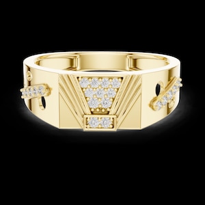 May include: A gold-colored ring with a geometric design. The ring features a central triangular section and two rectangular sections, all adorned with small, sparkling diamonds. The ring has a polished finish and a modern aesthetic.