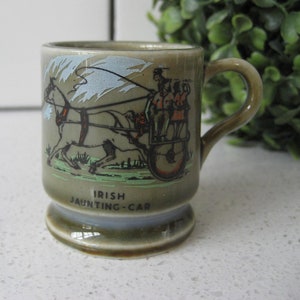 May include: A small green ceramic mug with a picture of a horse-drawn carriage and the words "Irish Jaunting-Car" on the front.