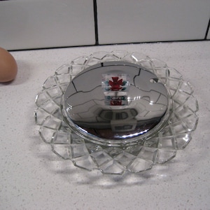 May include: A clear glass butter dish with a silver lid. The dish has a diamond pattern and the lid has a small handle.