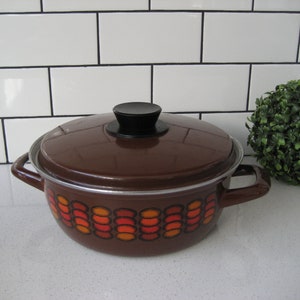 May include: Brown enamel pot with a lid and two handles. The pot has a geometric pattern of orange, red, and white circles.