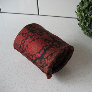 May include: A rolled up red and black patterned silk necktie.
