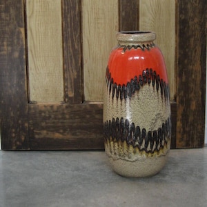 Puede incluir: Un jarrón grande de cerámica con un esmalte marrón, negro y naranja. El jarrón tiene un cuerpo redondeado y un cuello estrecho.