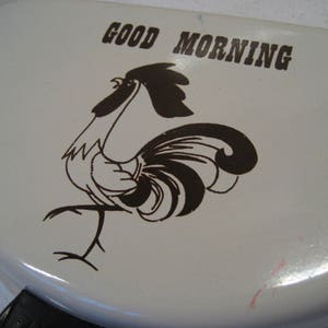 May include: White ceramic frying pan with a black rooster illustration and the text "GOOD MORNING".