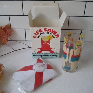 May include: A vintage "Life Saver" floating glass caddy set. The box features a red and white life preserver graphic. The set includes a clear glass with a design of people in swimsuits and a red and white striped floating caddy.